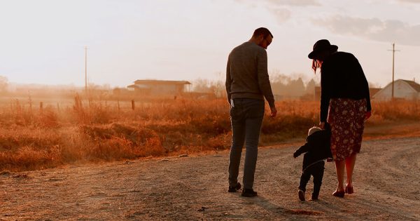 Man And Woman Walking With There Kid on a Dirt Road